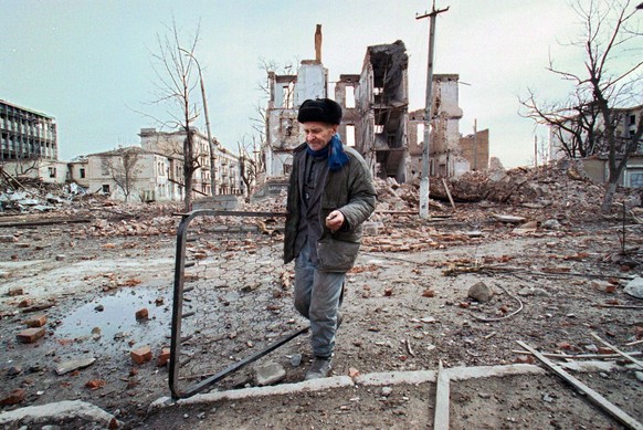 MOS04-20000324-GROZNY, CHECHNYA, RUSSIAN FEDERATION: A Chechen man carries the remains of a bed as he passes through a scene of total devastation in the Chechen capital Grozny, Friday 24 March 2000. R ...
