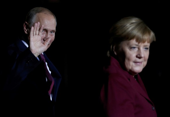 Russian President Vladimir Putin waves next to German Chancellor Angela Merkel as he arrives for talks on a stalled peace plan for eastern Ukraine at the chancellery in Berlin, Germany, October 19, 20 ...