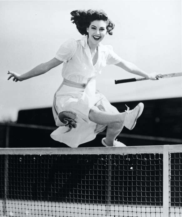American actor Ava Gardner (1922 - 1990) smiles as she jumps over the net on a tennis court, holding her racket, 1940s. (Photo by Hulton Archive/Getty Images)