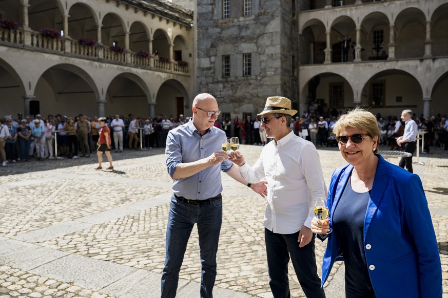 La presidente de la Confederation Viola Amherd, droite, le conseiller federal Ignazio Cassis, centre, et le chancelier Viktor Rossi, boivent un verre de vin valaisan avec la population valaisanne pend ...