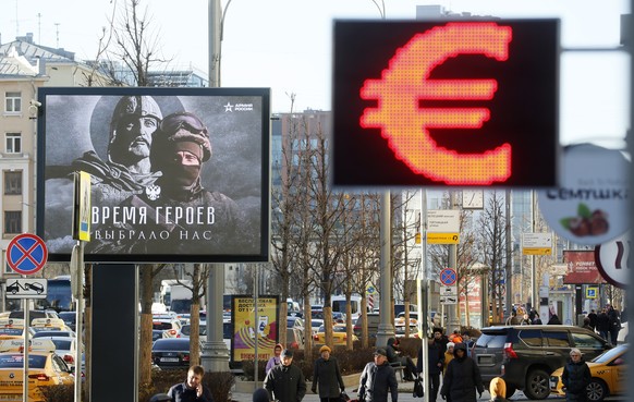 epa10305410 People walk in front of a currency exchange office with a Euro symbol and a billboard in support of the Russian army with a slogan reading &#039;Time of Heroes&#039;, in Moscow, Russia, 14 ...