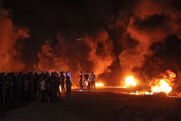 epa09434855 Palestinian protesters burn tyres during a demonstration along the border between the Gaza Strip and Israel, east Gaza City, late 28 August 2021 (issued 29 August 2021). For the first time ...