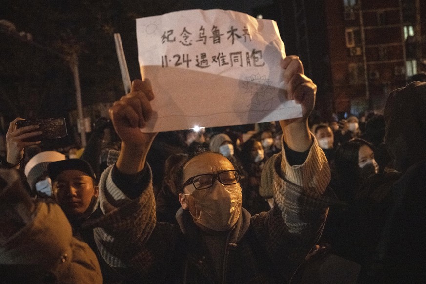 A protester holds up a sign which reads &quot;Commemorate Urumqi Nov 24 compatriots who died&quot; in Beijing, Sunday, Nov. 27, 2022. Protesters angered by strict anti-virus measures called for China& ...