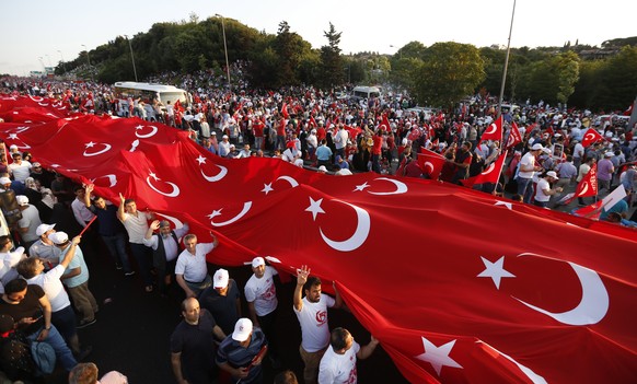 epa06089846 People hold a huge Turkish flag before a rally for the first anniversary of the failed coup attempt on Bosphorus Bridge in Istanbul, Turkey, 15 July 2017. The 15 July 2017 event marks the  ...
