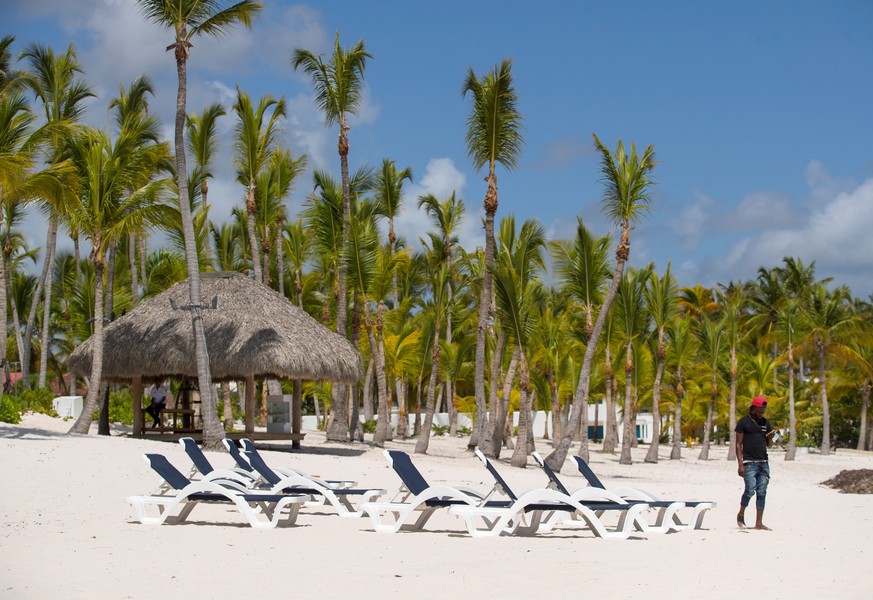 epa08557255 A hotel employee walks on the beach in Punta Cana, Dominican Republic, 20 July 2020. The Dominican President declared the national territory in a state of emergency for a period of 45 days ...