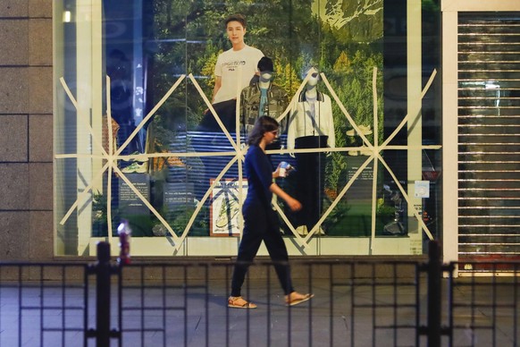 A woman walks past a fashion store with windows taped early in the morning, as a precaution against the approaching powerful tropical cyclone Saola, in Hong Kong, on Friday, Sept. 1, 2023. The Hong Ko ...