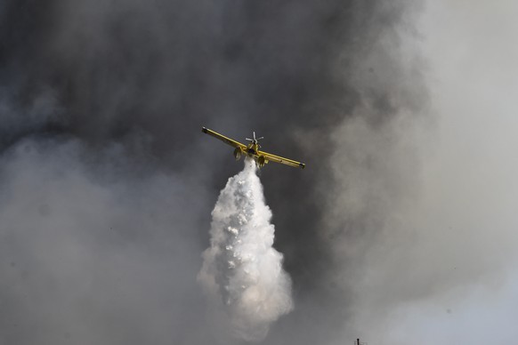 A firefighting airplane throws water near the village of Krestena south of Ancient Olympia, about 320 kilometers (200 miles) southwest of Athens, as authorities evacuate urgently another five villages in the area, on Sunday, July 24, 2022. There are at least six more fires burning across Greece, according to the fire service, with three of those burning for several days. (Giannis Spyrounis/ilialive.gr via AP)