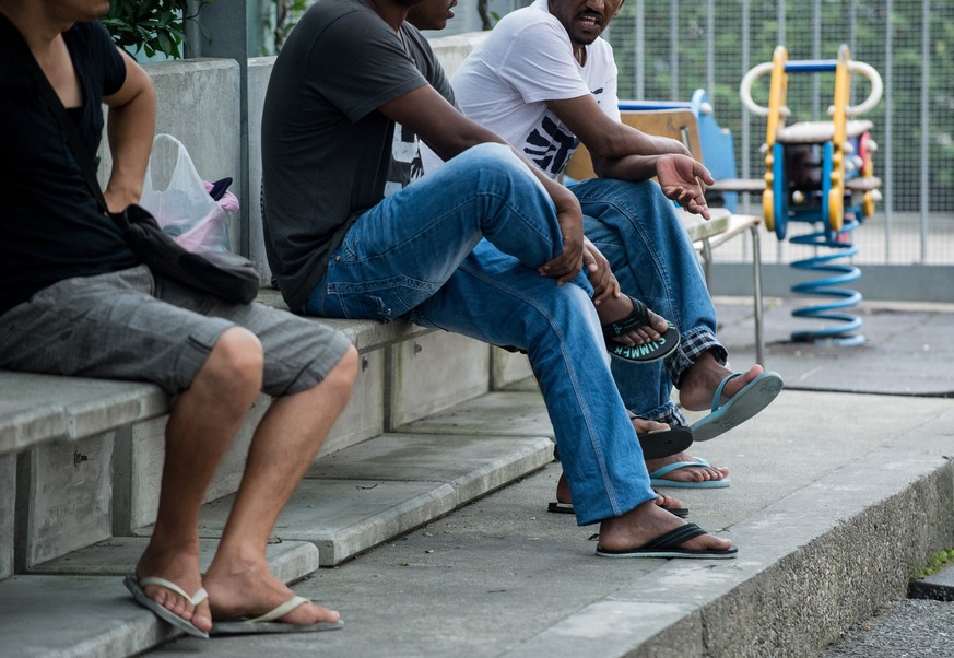 Asylbewerber sitzen am Mittwoch, 23. Juli 2014, im Hof des Empfangs- und Verfahrenszentrums Chiasso. Die Fluechtlinge, hauptsaechlich aus Afrika, hoffen im Empfangs- und Verfahrenszentrum fuer Asylbew ...