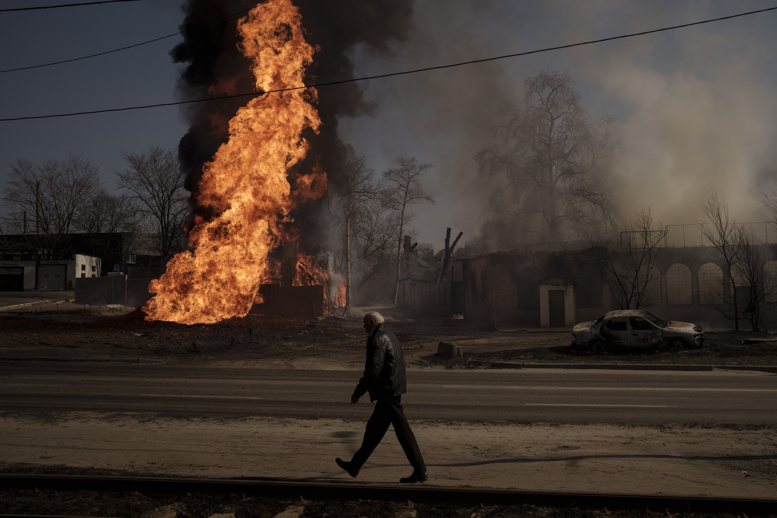 A man walks past flames and smoke rising from a fire following a Russian attack in Kharkiv, Ukraine, Friday, March 25, 2022. (AP Photo/Felipe Dana)