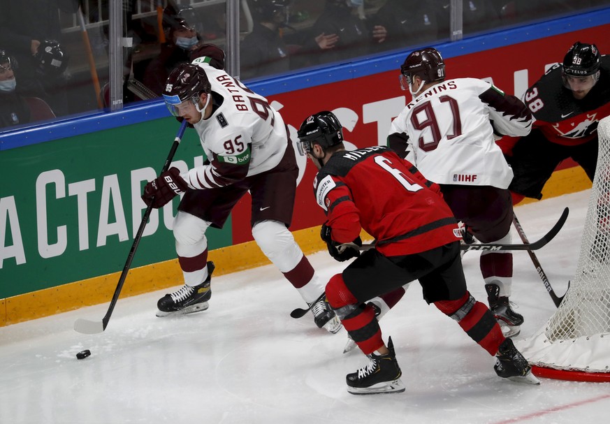 epa09218700 Mario Ferraro (R) and Colin Miller (2nd L) of Canada and Oskars Batna (L) and Ronalds Kenins of Latvia in action during the group B match between Canada and Latvia at the IIHF 2021 Ice Hoc ...