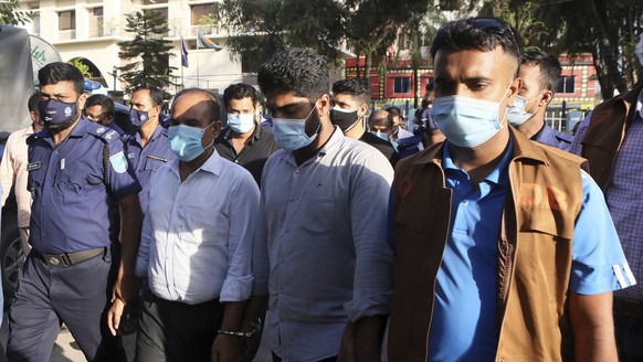 Two unidentified men, in center, are escorted by Bangladesh police officials to the court in Narayanganj, outside Dhaka, Bangladesh, Saturday, July 10, 2021. Police in Bangladesh arrested eight people ...