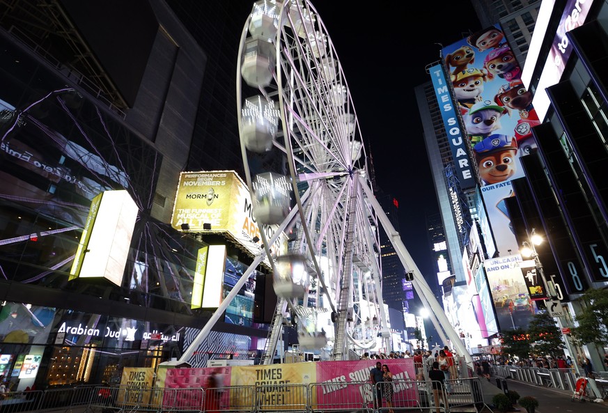 epa09429726 People take pictures in front of the 110 feet (33.5 meters) tall Times Square Wheel, a ferris wheel which was constructed in Times Square in New York, New York, USA, 25 August 2021. The at ...