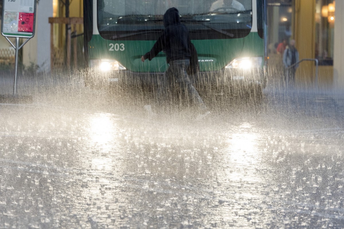 Une personne marche sous une pluie battante sur la place de la gare lors d'un episode orageux, ce mardi 30 aout 2022 a Morges. (KEYSTONE/Salvatore Di Nolfi)
