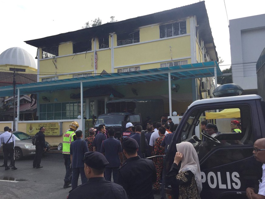 In this photo provided by @FRIENDOFBOMB, police prepare to bring victims out of an Islamic religious school after a fire on the outskirts of Kuala Lumpur, Malaysia, Thursday, Sept. 14, 2017. A fire de ...