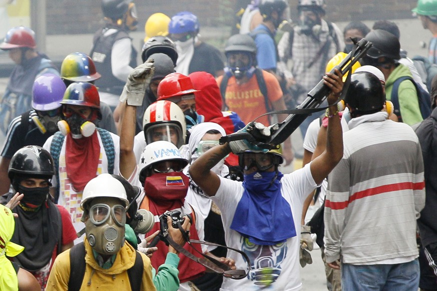 An anti-government demonstrator shows a shotgun taken from security forces during clashes in Caracas, Venezuela, Monday, May 8, 2017. The protest movement against President Nicolas Maduro, that has dr ...