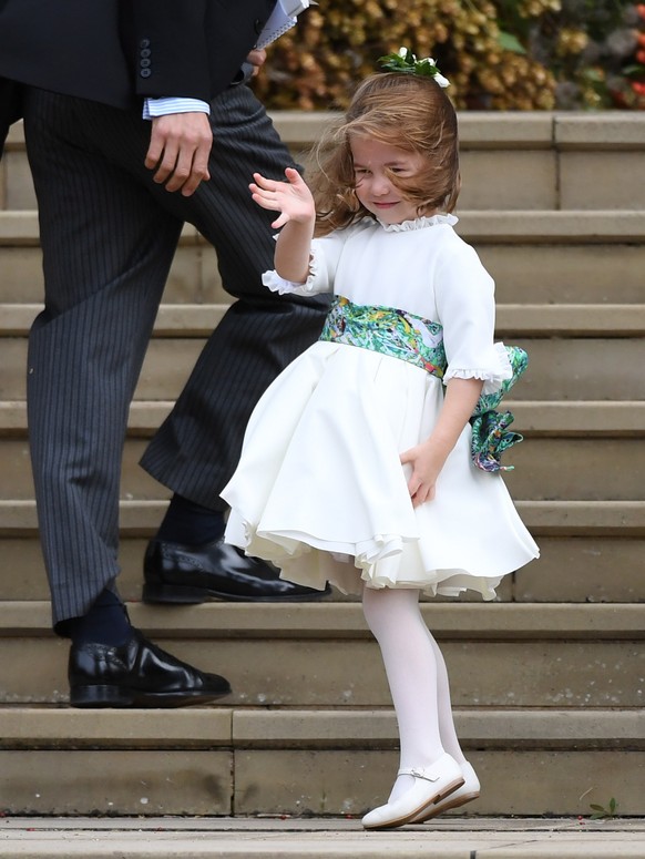epaselect epa07087830 Britain&#039;s Princess Charlotte waves as pageboys and flowergirls arrive for the royal wedding ceremony of her daughter, Princess Eugenie of York and Jack Brooksbank at St Geor ...
