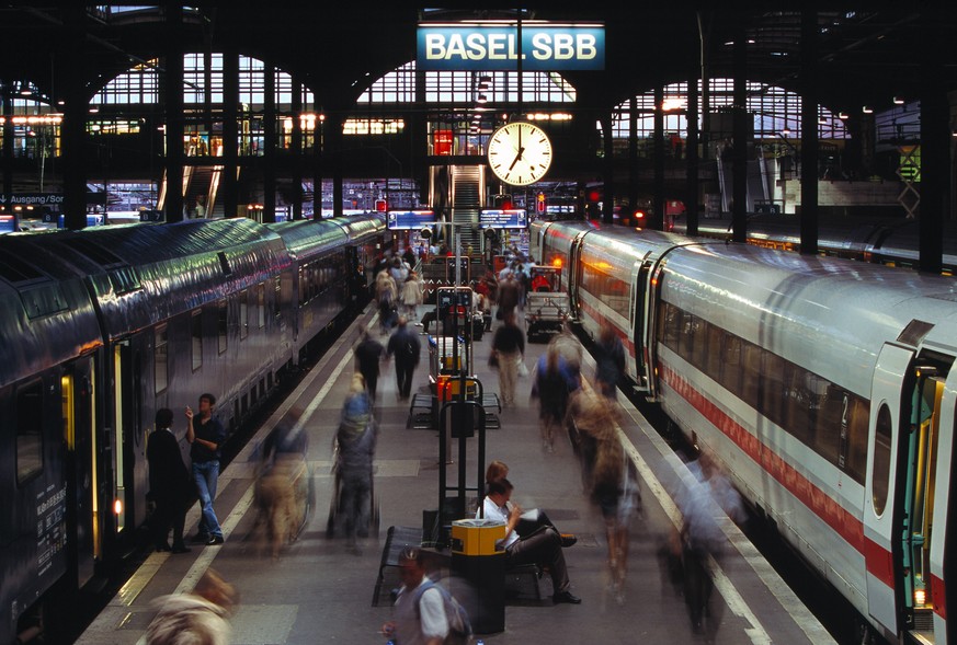 ZUM 75-JAEHRIGEN JUBILAEUM DER SBB BAHNHOFUHR (1944) STELLEN WIR IHNEN FOLGENES BILDMATERIAL ZUR VERFUEGUNG --- Auf dem Bahnsteig im Bahnhof Basel sind Reisende in der Abenddaemmerung auf dem Weg zu i ...