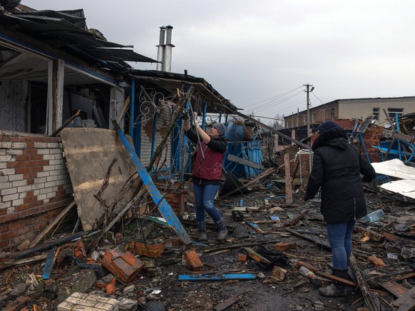 epa09861079 Taisia (L), cleans debris with her friends next to her house destroyed during the Russian invasion, in Boromlia village, at Trostyanets district which was recaptured by the Ukrainian army, ...