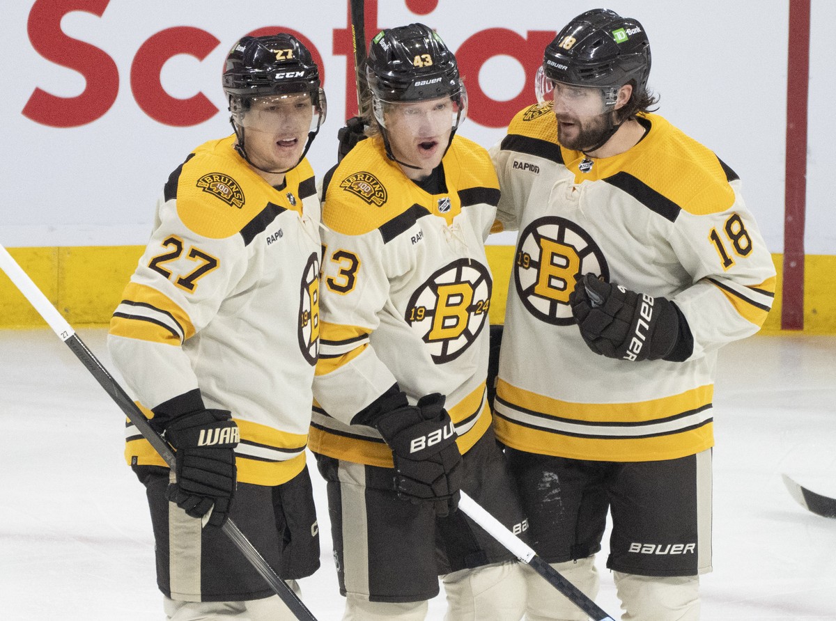 Boston Bruins' Danton Heinen, center, celebrates after his goal against the Montreal Canadiens with teammates Hampus Lindholm (27) and Pavel Zacha (18) during first-period NHL hockey game action  ...