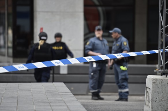 epa05894609 Swedish police officers are seen behind a cordoned off area after a truck reportedly crashed into a department store in central Stockholm, Sweden, 07 April 2017. A truck has driven into cr ...