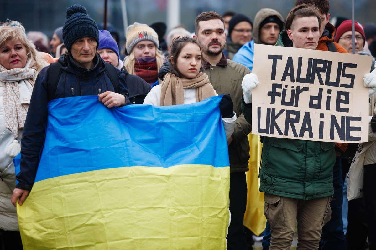 epa11061140 A participant holds a placard reading 'Taurus for Ukraine', asking for delivery of the Taurus cruise missile system to Ukraine, while others display an Ukrainian national flag du ...
