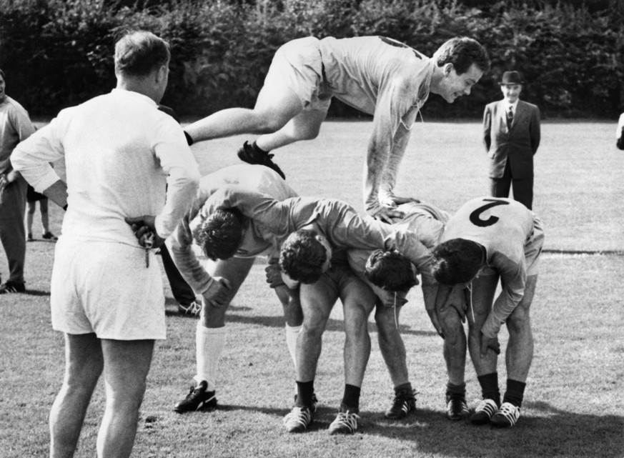 Jakob &quot;Koebi&quot; Kuhn setzt am 10. Juli 1966 mit einem gewaltigen Sprung vor den Augen des Trainers der Schweizer Fussball Nationalmannschaft, Alfredo Foni, links, ueber seine Kameraden hinweg. ...