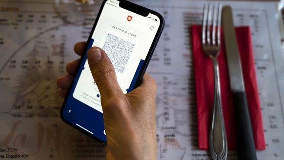 Une personne tient dans sa main un smartphone avec l&#039;application Certifact Covid suisse et un certificat light dans un restaurant ce vendredi 10 septembre 2021 a Rances dans le canton de Vaud. De ...