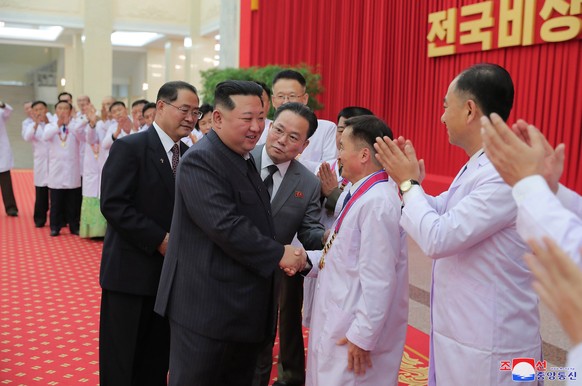 epa10115148 A photo released by the official North Korean Central News Agency shows North Korean leader Kim Jong Un (C) shaking hands with health officials and scientists in the anti-epidemic and publ ...