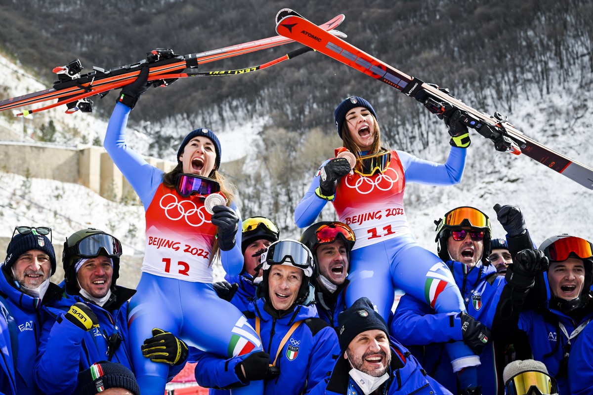 epa09757717 Silver medalist Sofia Goggia of Italy, left, and bronze medalist Nadia Delago of Italy, right, celebrate with member of italian team after the victory ceremony of the women's downhill ...