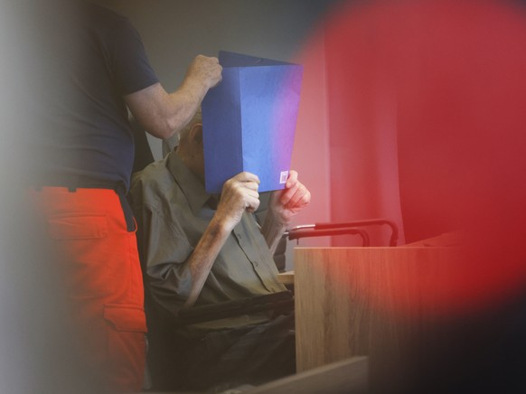 The accused Josef S. covers his face as he sits at the court room in Brandenburg, Germany, Tuesday, June 28, 2022. A 101-year-old man has been convicted of 3,518 counts of accessory to murder for serv ...