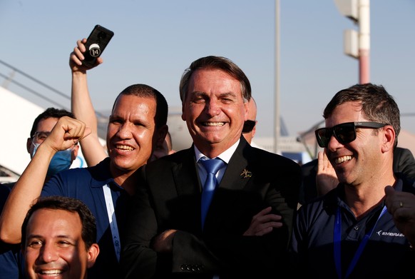 epa09581560 Brazilian President Jair Bolsonaro (C) tours at the exhibition of the Dubai Airshow 2021 at Dubai World Central - Al Maktoum International Airport, in Jebel Ali, Dubai, United Arab Emirate ...