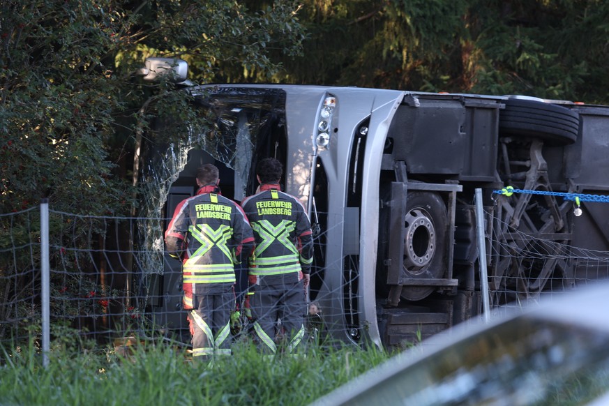 27.09.2026, Bayern, Buchloe: Feuerwehr steht neben einem umgekippten Reisebus an der A96. Zwei Menschen seien dabei ums Leben gekommen, mehrere Menschen verletzt worden, sagte ein Polizeisprecher der  ...