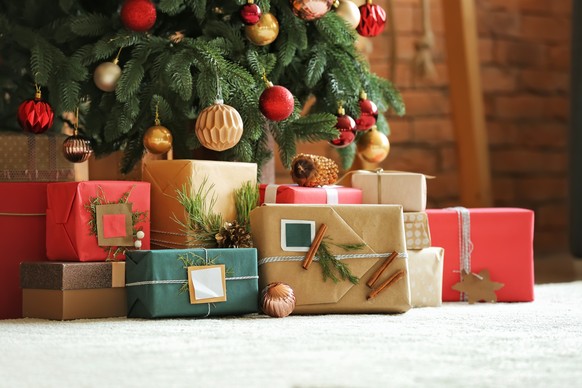 Schöne Weihnachtsgeschenke unter Tannenbaum auf dem Boden im Zimmer