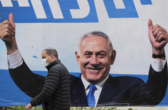 epa09081409 A man walks by an elections billboard showing Israeli prime minister Benjamin Netanyahu in Jerusalem, 18 March 2021. Israel is expected to hold legislative elections on 23 March 2021 to el ...