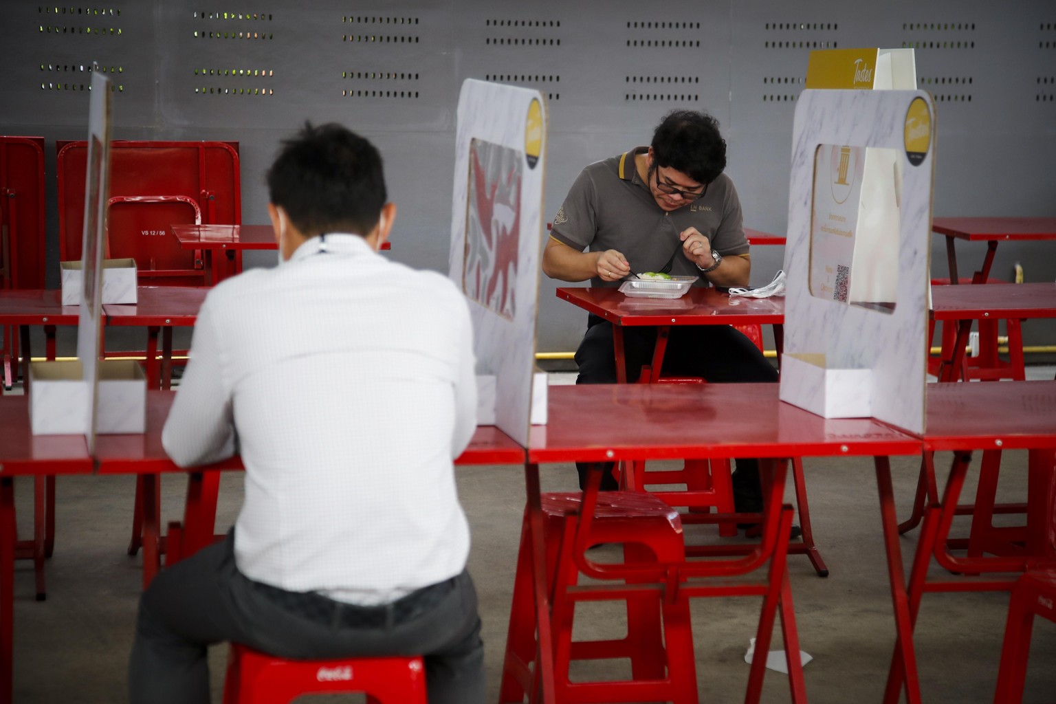 epa08444386 People eat lunch on tables partitioned by cardboard and plastic sheets in order to enforce social distancing in Bangkok, Thailand, 26 May 2020. Most restaurants have resorted to the use of ...