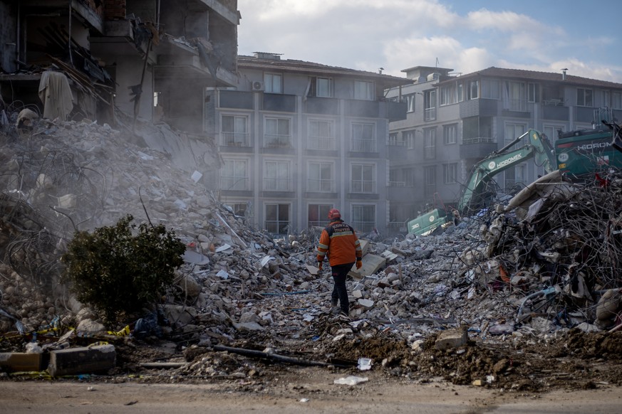 epa10478186 A rescuer walks on debris of collapsed buildings after a powerful earthquake, in Hatay, Turkey, 19 February 2023. More than 46,000 people have died and thousands more are injured after two ...