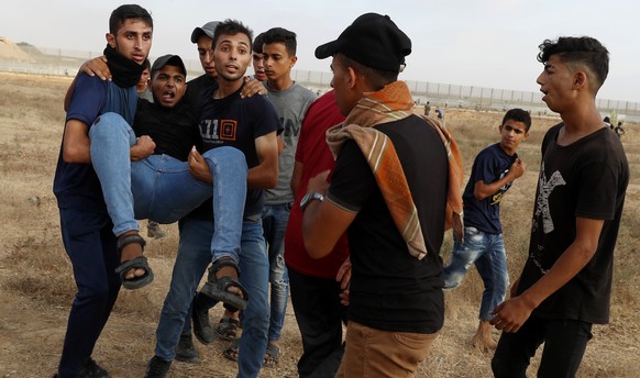 Protestors evacuate a wounded from the fence of Gaza Strip border with Israel, during a protest marking the anniversary of a 1969 arson attack at Jerusalem&#039;s Al-Aqsa mosque by an Australian touri ...