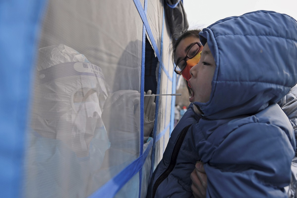 In this photo released by Xinhua News Agency, a worker wearing a protection suit collects samples from a child during a mass coronavirus testing in north China's Tianjin municipality, Sunday, Jan ...
