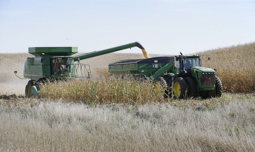 A farmer dumps corn in a grain trailer as he harvests a field, Monday, Oct. 7, 2013, near Clear Lake, Iowa. Farmers and livestock producers use the reports put out by the National Agriculture Statisti ...