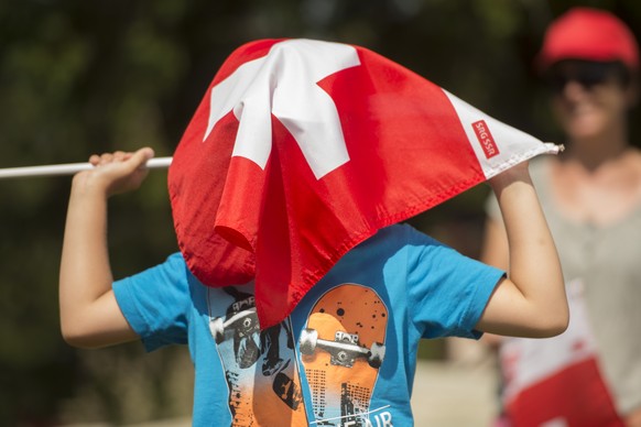 Ein Junge schuetzt sich mit einer Schweizer Fahne vor der Hitze am Samstag, 4. Juni 2015 auf der Aelggi Alp, dem geographischen Zentrum der Schweiz, wo Bundesrat Didier Burkhalter offiziell als Schweizer des Jahres 2014 gefeiert wird.   (KEYSTONE/Urs Flueeler)