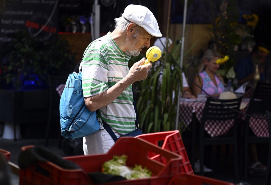 epa10753530 A man uses a fan at the market in Campo de Fiori during a heat wave in Rome, Italy, 18 July 2023. Italy is facing the third heatwave of the summer on 18 July bringing record temperatures.  ...