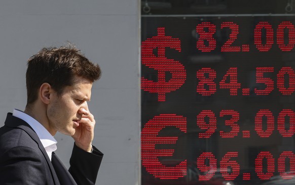 epa12044577 A man walks in front of an exchange office with an electronic panel displaying currency exchange rates against the Russian ruble in Moscow, Russia, 21 April 2025. On the morning of 21 Apri ...