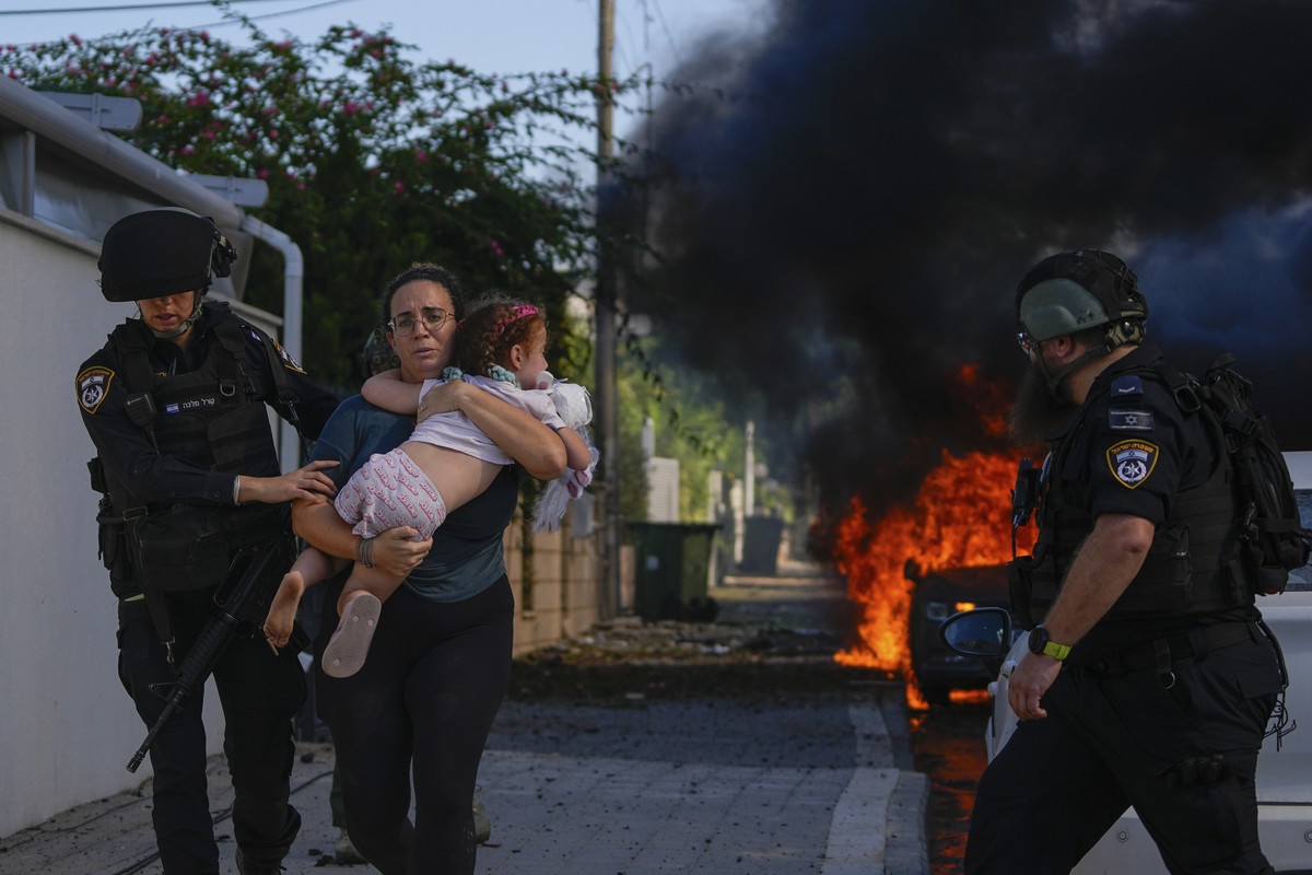FILE - Police officers evacuate a woman and a child from a site hit by a rocket fired from the Gaza Strip, in Ashkelon, southern Israel, Saturday, Oct. 7, 2023. The rockets were fired as Hamas announc ...