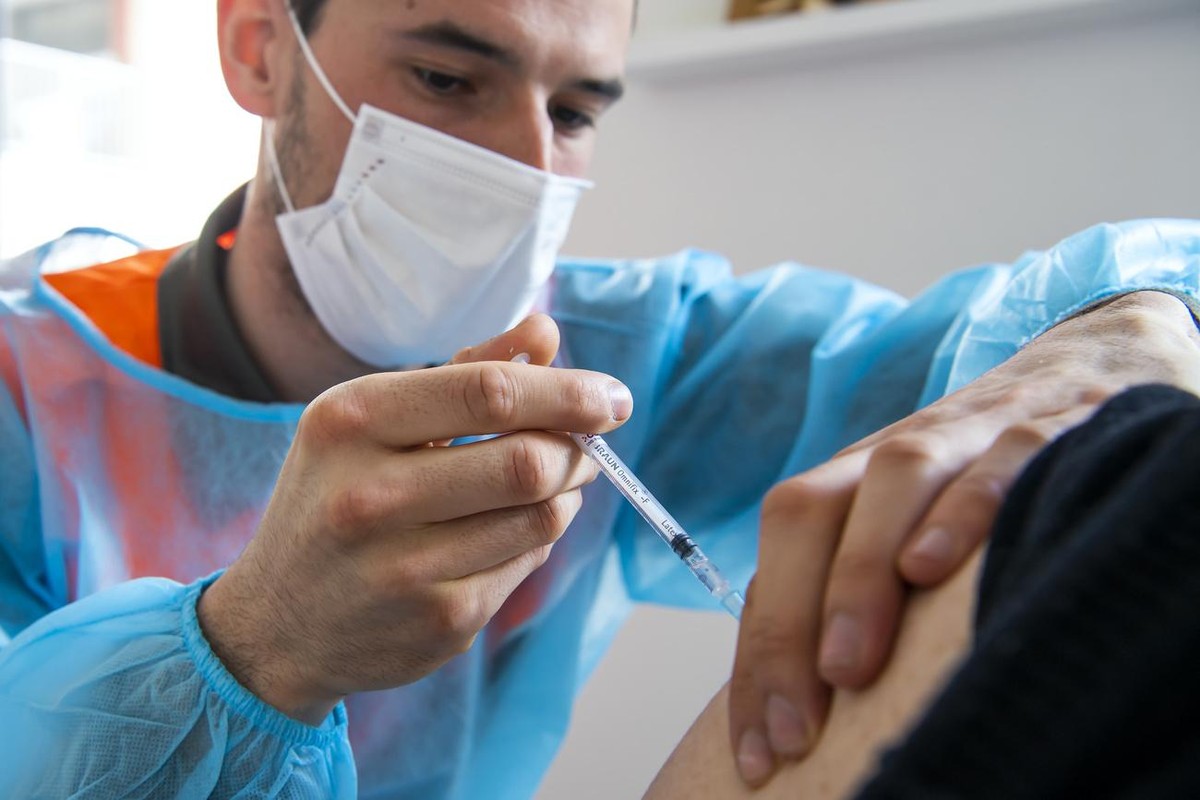 Un membre d'une equipe mobile de vaccination de la protection civile vaudoise, PC, vaccine une femme a l'aide du vaccin Pfizer-BioNTech dans les logements proteges Les Saules, lors du dernie ...