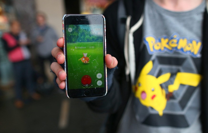 epa05432916 A gamer sporting a shirt with an image of fictional creature Pikachu shows his mobile phone as he plays Pokemon Go near the Sydney Opera House in Sydney, New South Wales, Australia, 20 Jul ...