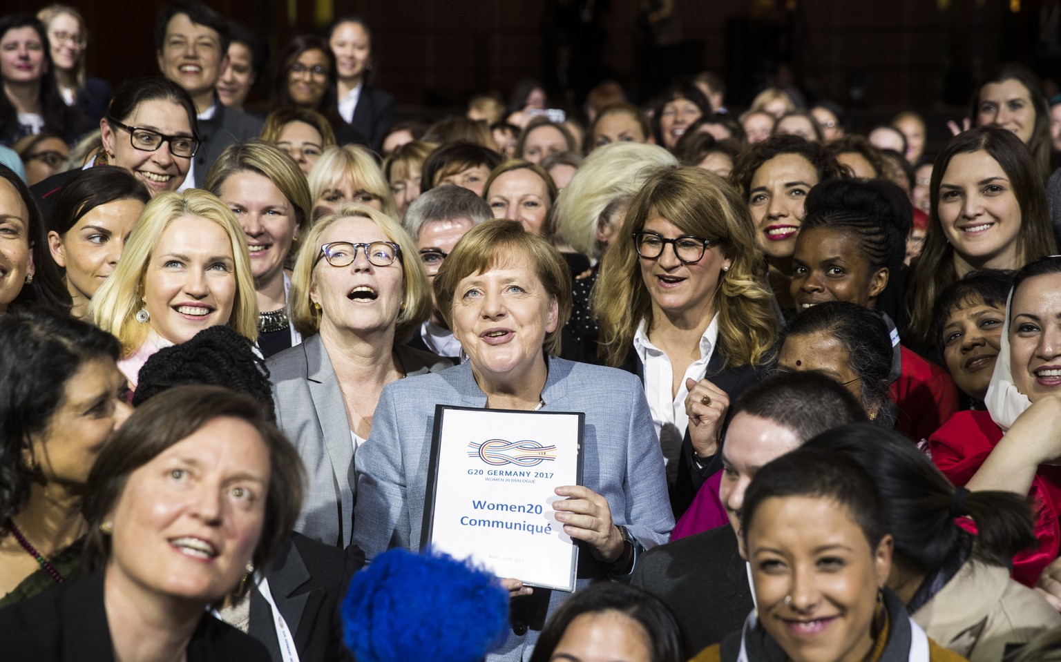German Chancellor Angela Merkel, center, holds the communique as she poses with delegates for a group photo at the end of the W20 summit 2017 in Berlin, Germany, Wednesday, April 26, 2017. (Odd Anders ...