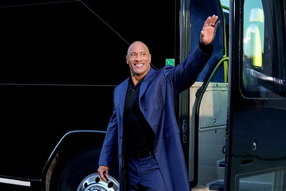 The Rock (Dwayne Johnson) steht vor einem Bus und winkt
