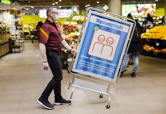 Lars Heer, Leiter Food, verschiebt ein Hinweisschild zur Maskenpflicht in der Migros am Limmatplatz, am Mittwoch, 16. Februar 2022 in Zuerich. (KEYSTONE/Michael Buholzer)