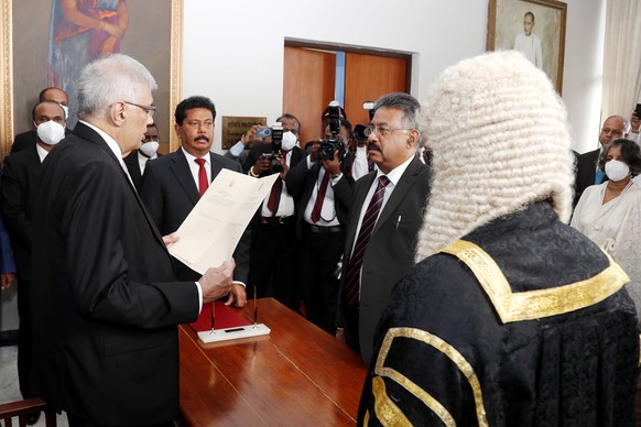 epa10083551 A handout photo made available by the Sri Lankan Parliament Media Unit shows Ranil Wickremesinghe (L) taking the oath as President of Sri Lanka in front of Chief Justice Jayantha Jayasuriy ...