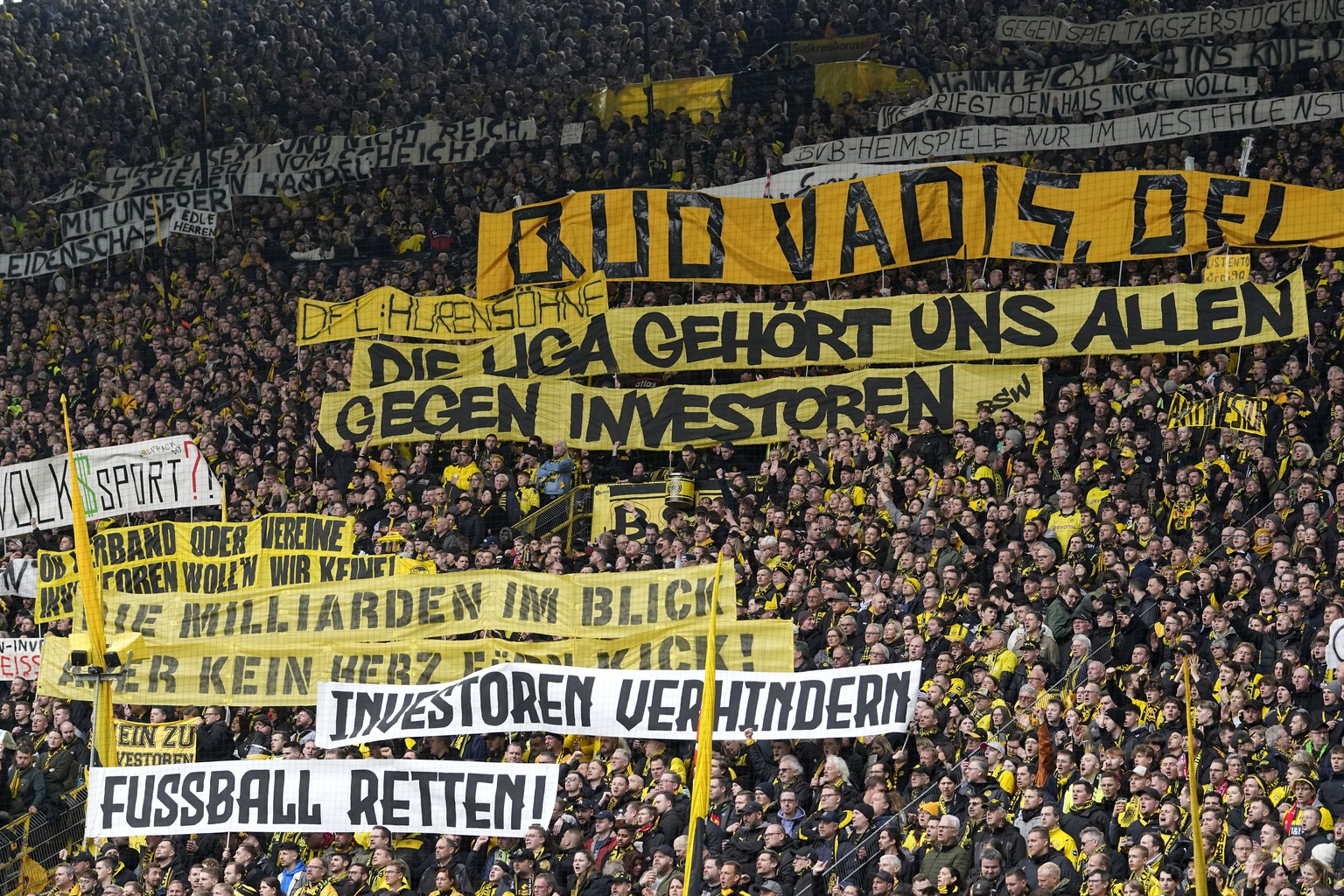 FILE - Fans hold up banners protesting against investors in German soccer during the German Bundesliga soccer match between Borussia Dortmund and Union Berlin in Dortmund, Germany, Saturday, April 8,  ...